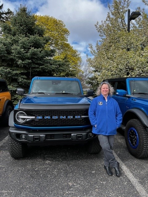 A woman poses next to a blue Ford Bronco